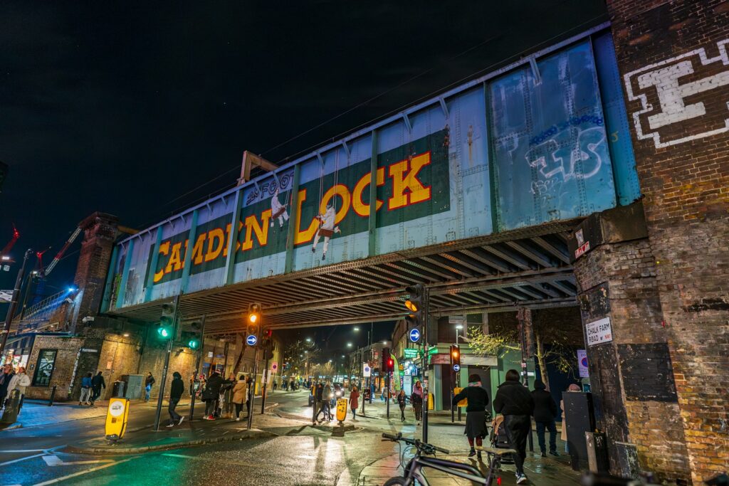 A group of people walking across a street under a bridge